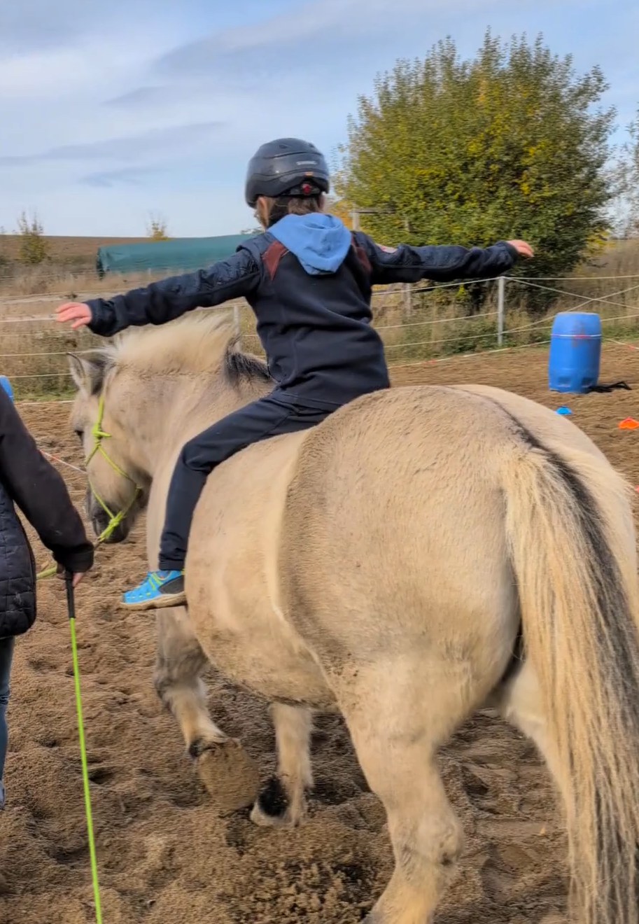 Kind auf dem Pony, Arme ausgebreitet
